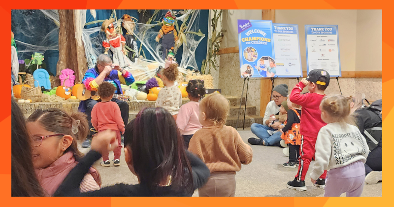 Children dance to music in a big room.